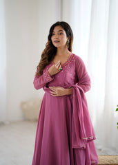 Woman wearing a pink traditional outfit with intricate detailing in a bright room.
